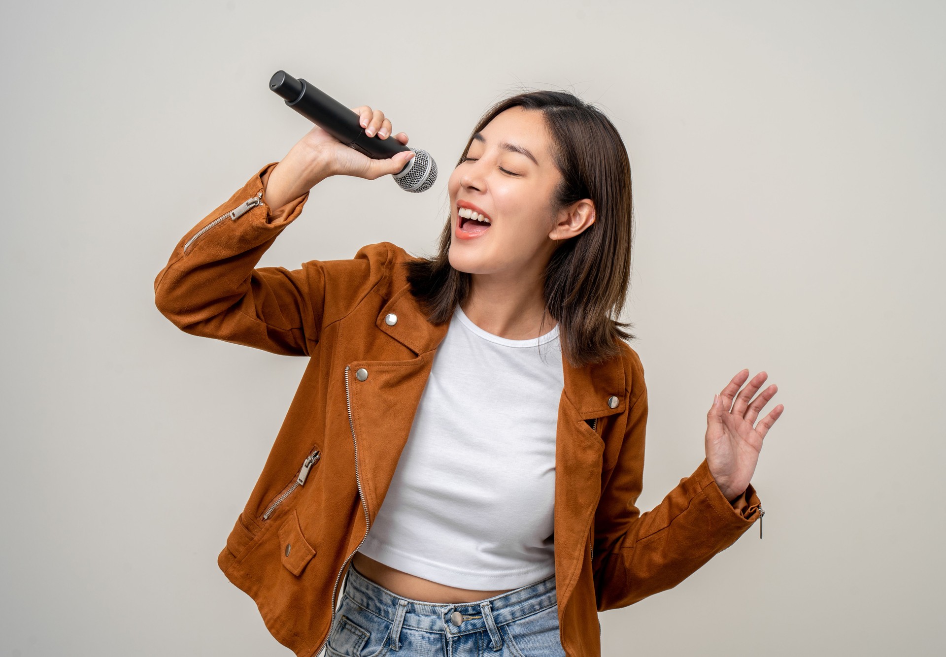 Happiness young asian woman singing song. Artist vocalist singer on isolated background. Confident woman public speaking talking with microphone in studio.